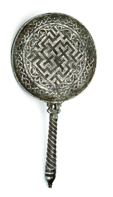 تکرار «علی» به خط کوفی منقوش شده در پشت «آینه سیمین» همراه با تزئینات اسلیمی گیاهی